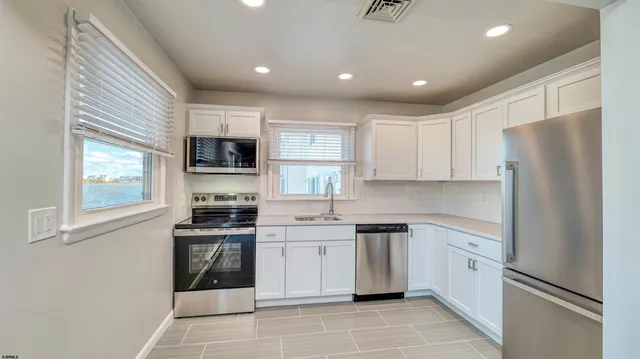 a kitchen with white cabinets stainless steel appliances and a window