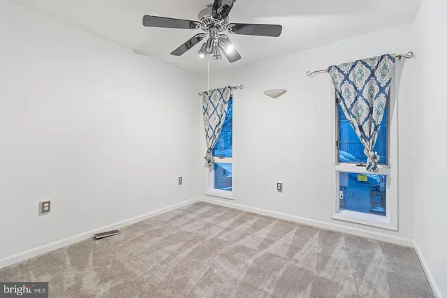 an empty room with windows and fan