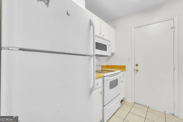 a view of a kitchen with white cabinets and white appliances