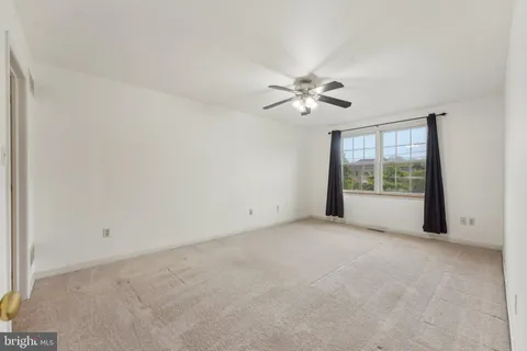 an empty room with chandelier fan and windows