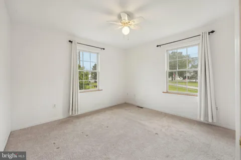 an empty room with windows and ceiling fan