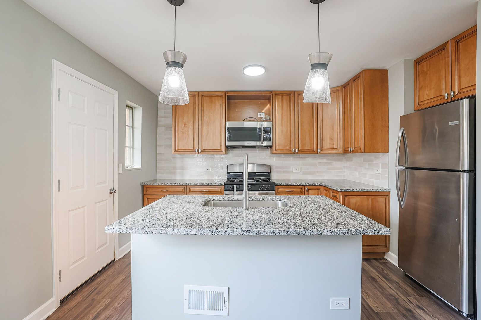 746 Walnut Street, Unit 2E Waukegan, IL 60085 - Photo 8 of 21 a kitchen with kitchen island a refrigerator a stove a sink cabinets and wooden floor