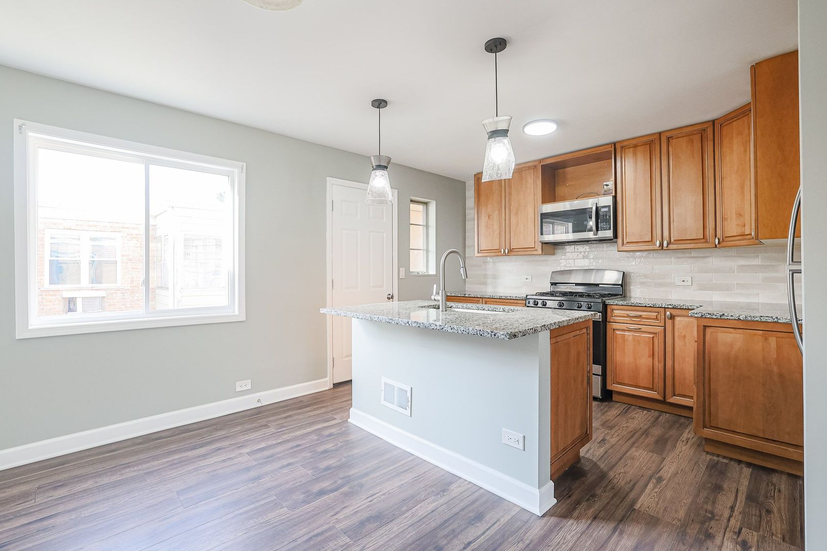 746 Walnut Street, Unit 2E Waukegan, IL 60085 - Photo 10 of 21 a kitchen with kitchen island granite countertop wooden floors white cabinets and stainless steel appliances