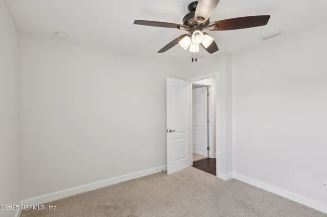 an empty room with a chandelier fan and a ceiling fan