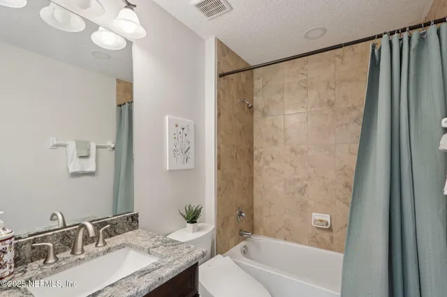 a bathroom with a granite countertop sink a toilet and shower