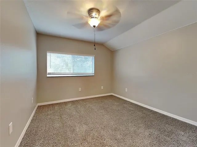 an empty room with a chandelier fan and windows