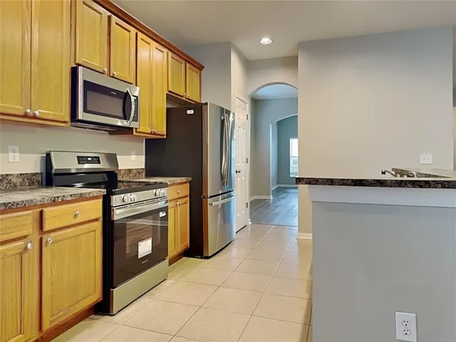 a kitchen with stainless steel appliances granite countertop a refrigerator a stove top oven and sink