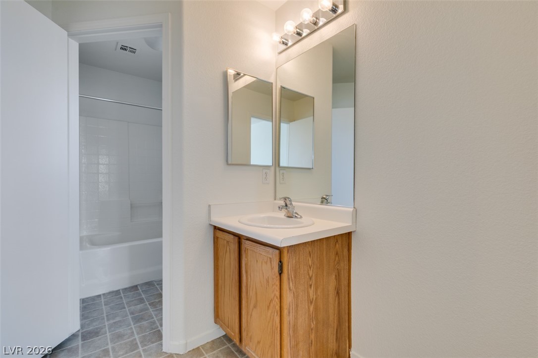 4957 Miners Ridge Drive Las Vegas, NV 89122 - Photo 28 of 39 Functional bathroom vanity with a basin and a bathtub in the background.