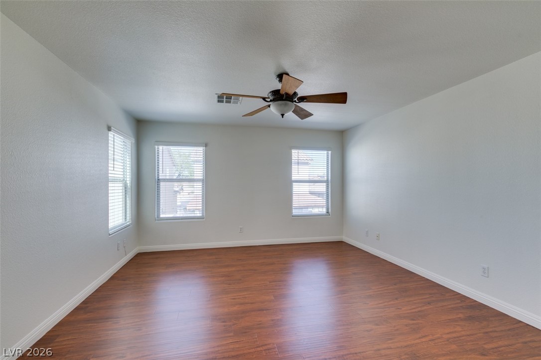 4957 Miners Ridge Drive Las Vegas, NV 89122 - Photo 30 of 39 An empty room features warm wood flooring and ample natural light through multiple windows.