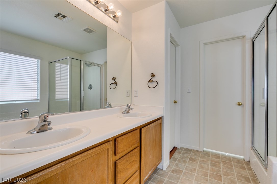 4957 Miners Ridge Drive Las Vegas, NV 89122 - Photo 33 of 39 This bathroom features dual sinks and a spacious shower, blending practicality with a crisp, clean aesthetic.