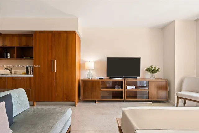 a living room with furniture a flat screen tv and kitchen view