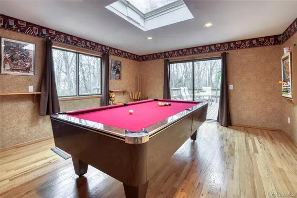 a room with pool table windows and wooden floor