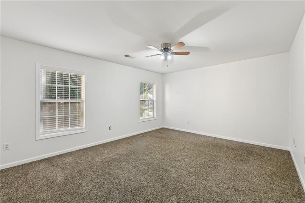 2435 Cobble Creek Lane Grayson, GA 30017 - Photo 33 of 39 an empty room with windows and chandelier fan