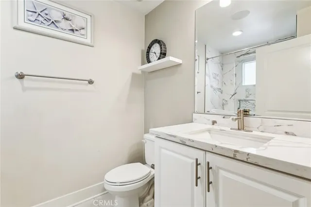 a bathroom with a granite countertop sink toilet and a mirror