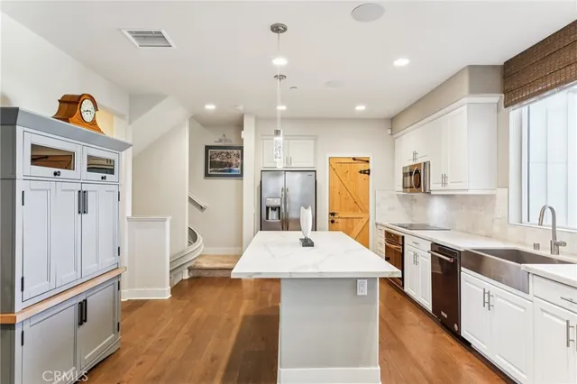 a kitchen with stainless steel appliances kitchen island granite countertop a refrigerator and a sink