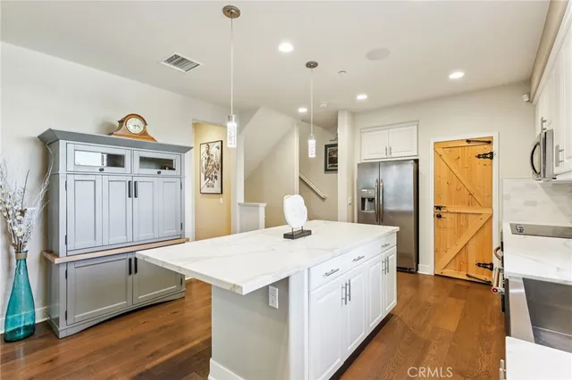 a kitchen with a refrigerator a sink and wooden floor