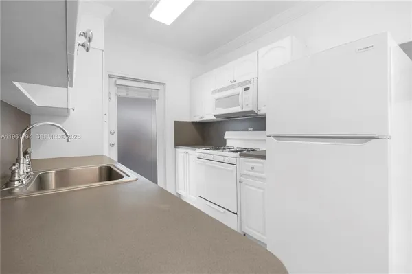 a kitchen with a refrigerator sink and cabinets