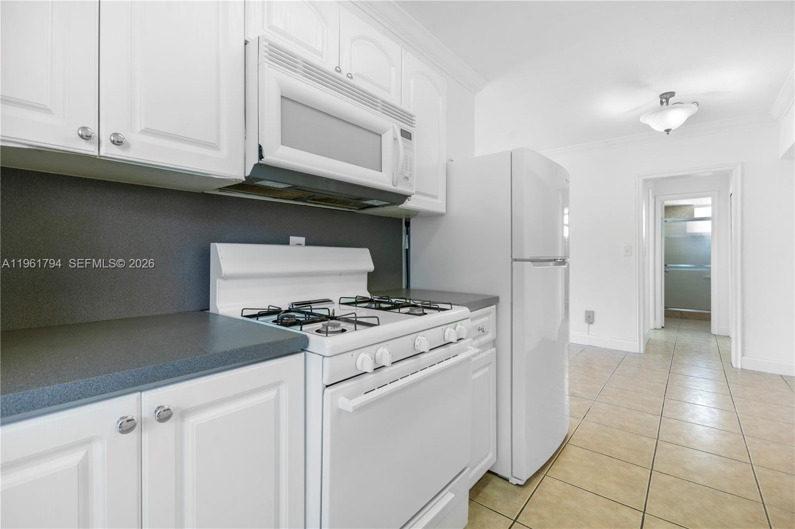 315 69th Street, Unit 112 Miami Beach, FL 33141 - Photo 17 of 20 a kitchen with stainless steel appliances granite countertop a stove and a white cabinets