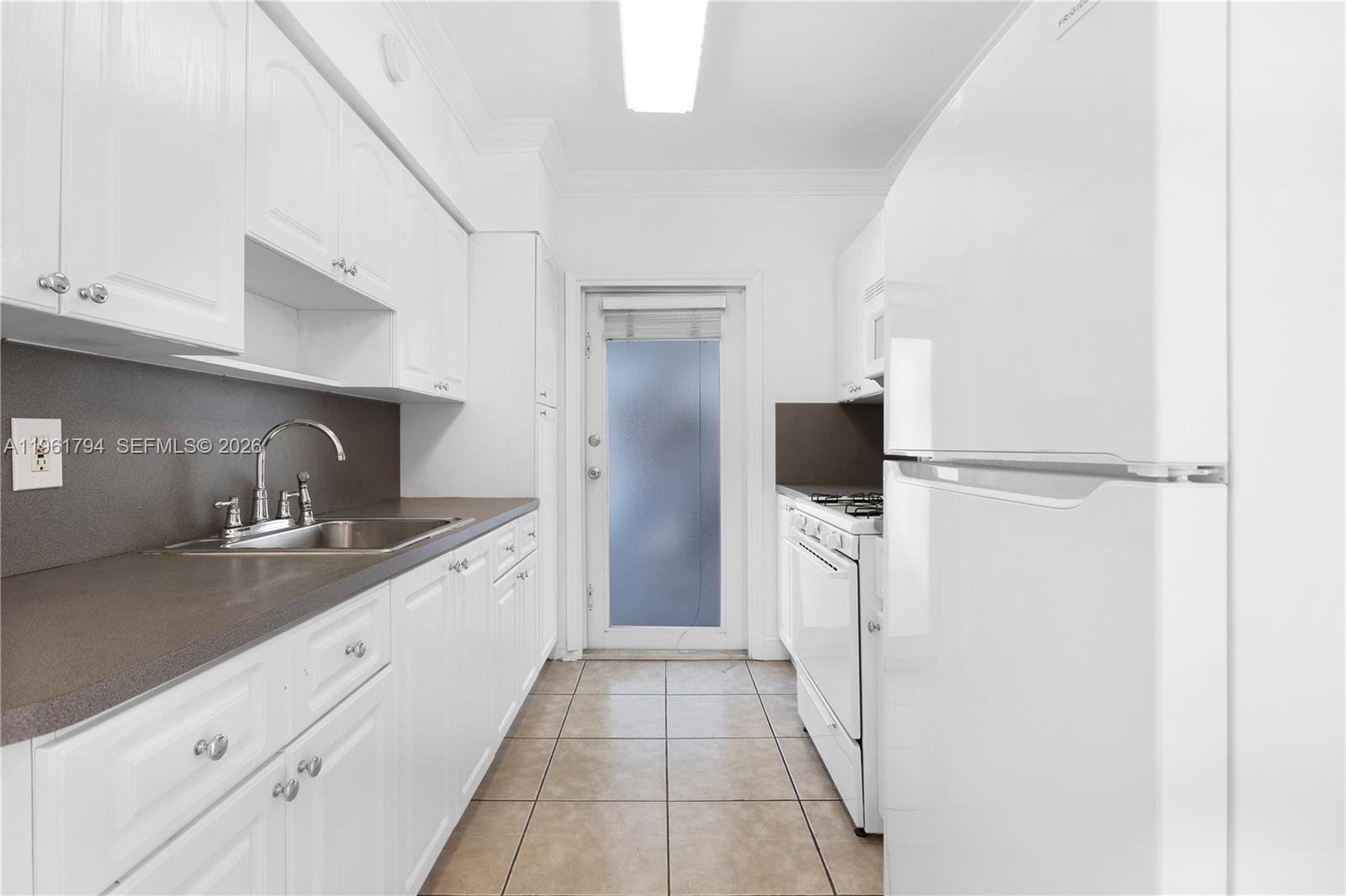 315 69th Street, Unit 112 Miami Beach, FL 33141 - Photo 2 of 20 a large kitchen with a sink and refrigerator