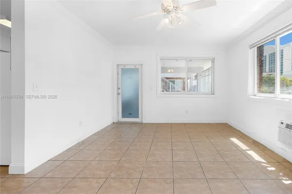 an empty room with chandelier fan and windows