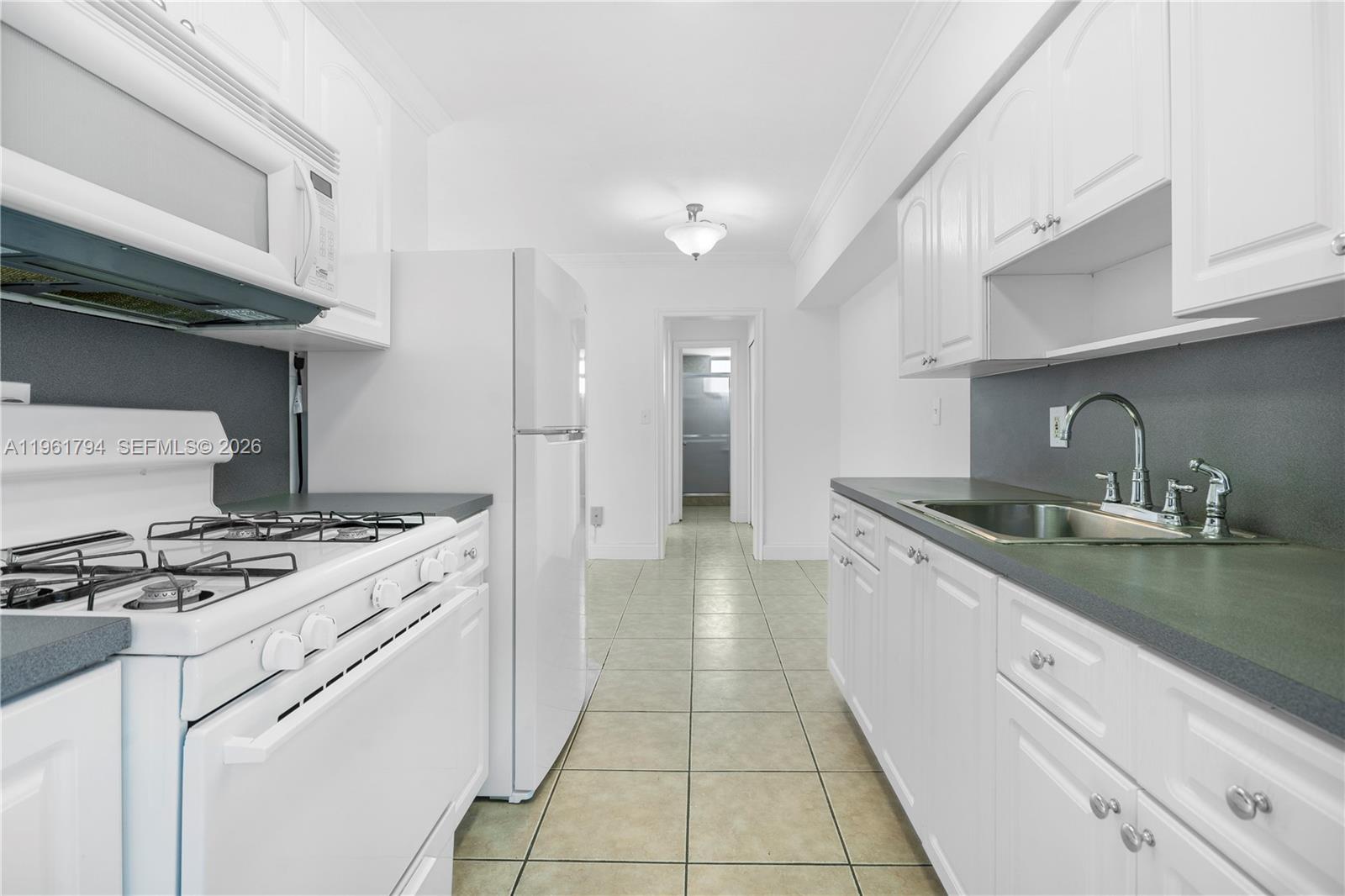 315 69th Street, Unit 112 Miami Beach, FL 33141 - Photo 8 of 20 a kitchen with a stove top oven and cabinets