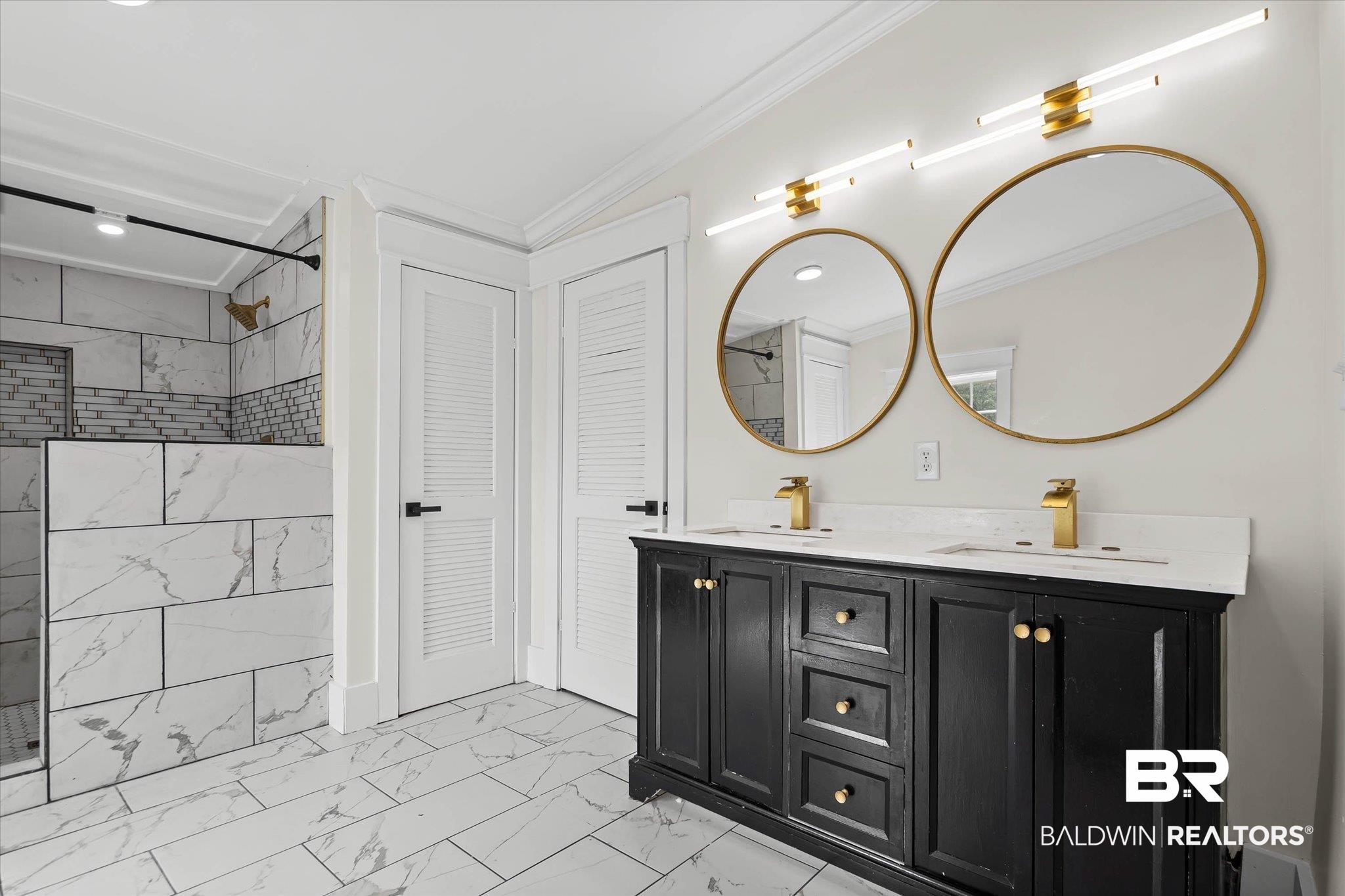 9230 McLeod Road Mobile, AL 36695 - Photo 12 of 20 Double vanity with black cabinetry and gold-tone hardware, featuring a white countertop, dual vessel sinks, and round gold-framed mirrors