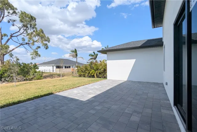 a view of yellow house with a yard and potted plants