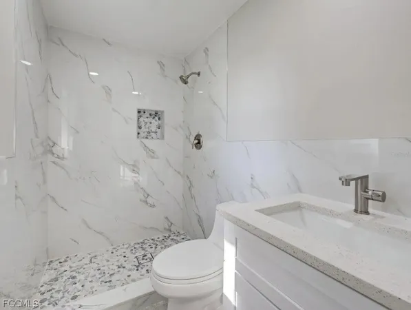 a bathroom with a granite countertop sink toilet and shower