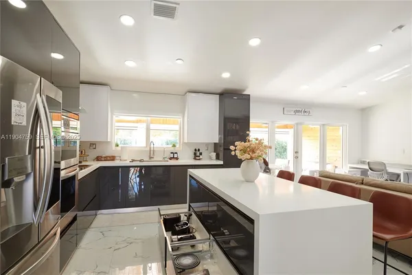 a kitchen with stainless steel appliances a sink a stove a refrigerator cabinets and a counter top space