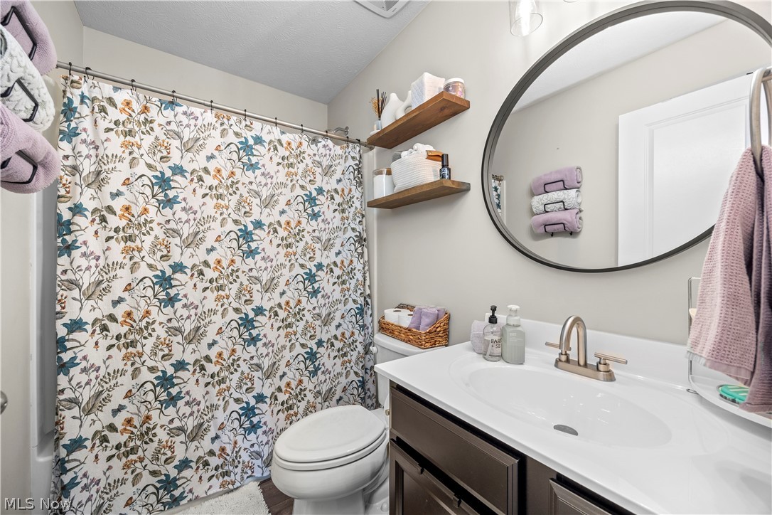 2161 Fowl Road Elyria, OH 44035 - Photo 24 of 46 Bathroom featuring a vanity with an integrated sink, a circular mirror, and two wall-mounted wood-finish shelves