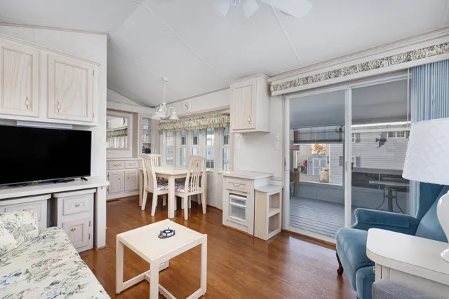 a living room with furniture a flat screen tv and kitchen view