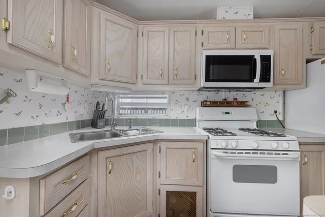 a kitchen with stainless steel appliances granite countertop a sink a stove a microwave oven and white cabinets