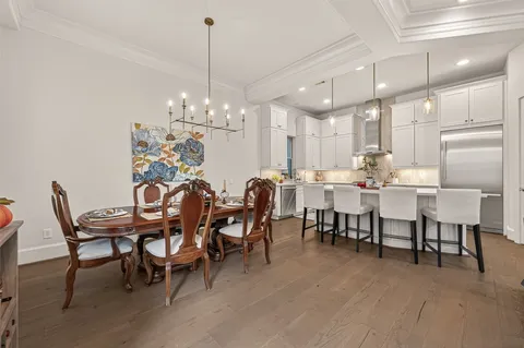 a view of a dining room and livingroom view with furniture wooden floor a chandelier