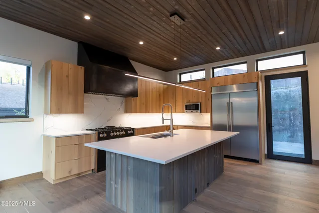 a kitchen with stainless steel appliances granite countertop a sink a counter space and a refrigerator
