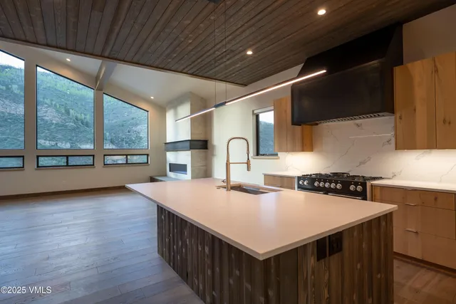 a kitchen that has a sink a stove and a wooden floor with wooden cabinet