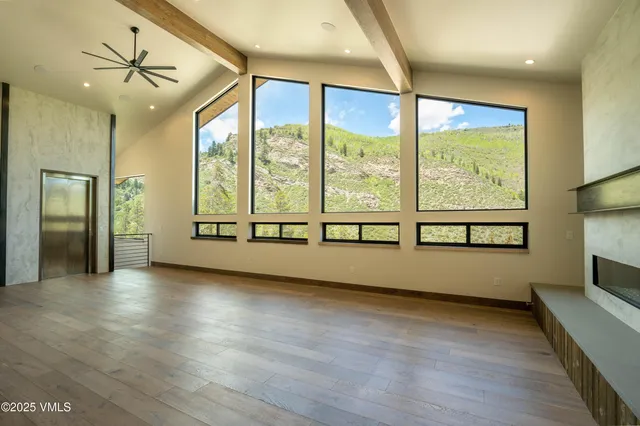 a view of an empty room with a window and wooden floor