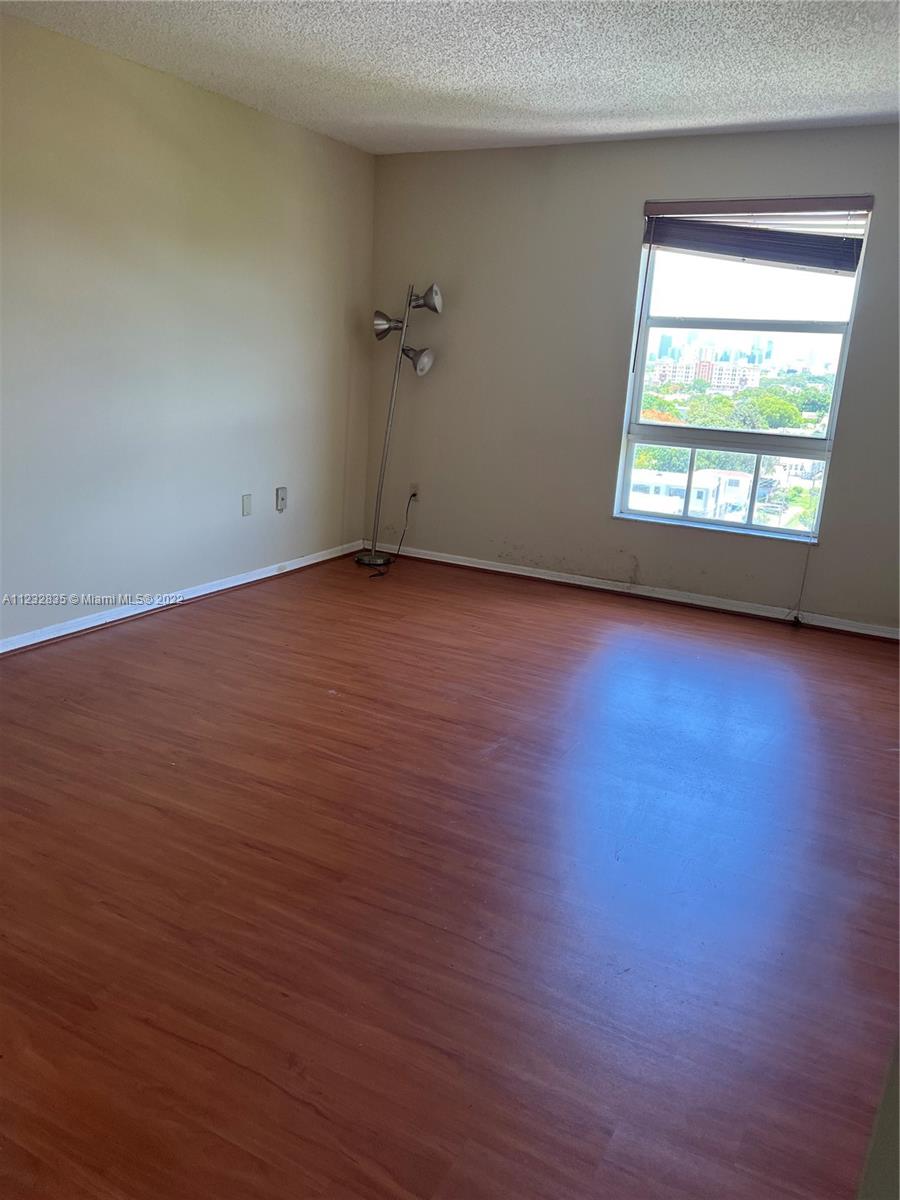 2351 Douglas Road, Unit 910 Miami, FL 33145 - Photo 21 of 24 an empty room with wooden floor and windows