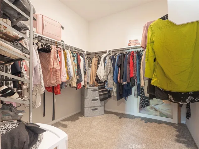 a view of walk in closet with clothes and shoes