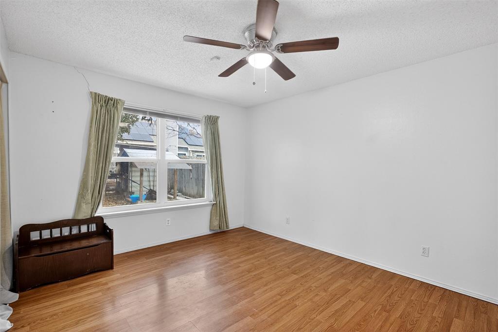 6813 Haltom Road Fort Worth, TX 76137 - Photo 6 of 14 a view of an empty room with a window and wooden floor