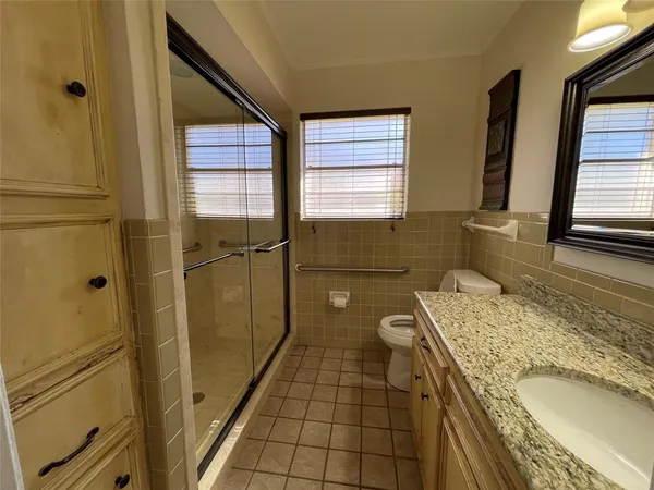 a bathroom with a granite countertop sink a toilet and shower