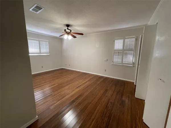 a view of empty room with wooden floor and fan