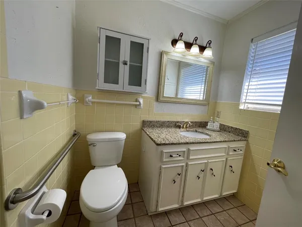 a bathroom with a granite countertop toilet sink and mirror