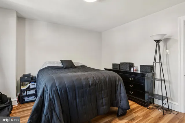 a bedroom with a bed and dresser with wooden floor