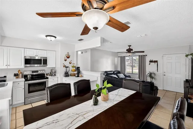 a kitchen with stainless steel appliances granite countertop a stove refrigerator a sink dishwasher a dining table and chairs with wooden floor