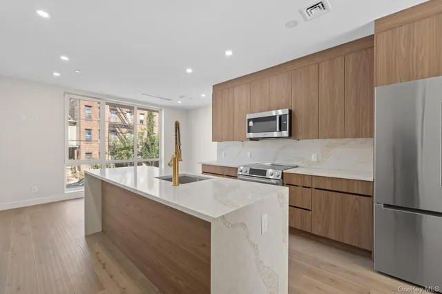 a kitchen with stainless steel appliances granite countertop a refrigerator a sink dishwasher a stove with wooden cabinets and floors