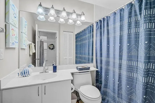 a bathroom with a toilet a sink a mirror a vanity and shower