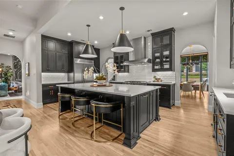 a kitchen with stainless steel appliances granite countertop a stove a refrigerator a kitchen island a dining table and chairs with wooden floor