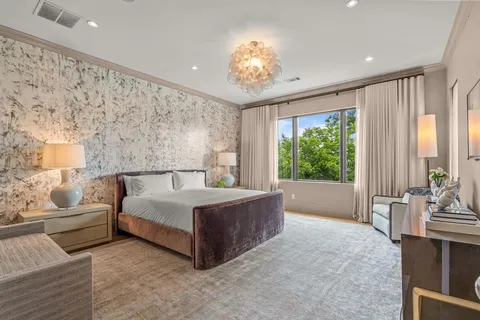 a spacious bedroom with a large bed and a chandelier