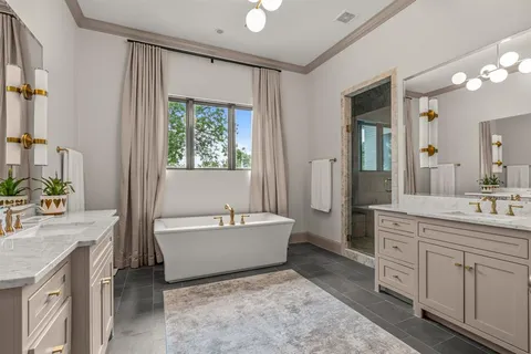 a spacious bathroom with a double vanity sink a mirror a bathtub and next to a window