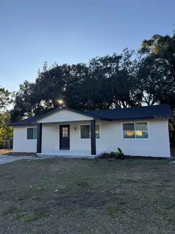 a front view of house with yard and trees in the background